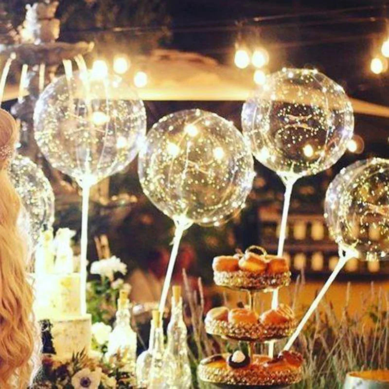 A display of clear, shimmering balloons on sticks for weddings and celebrations.