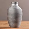 A modern ceramic flower vase with horizontal ridged texture in black and white on a wooden surface.