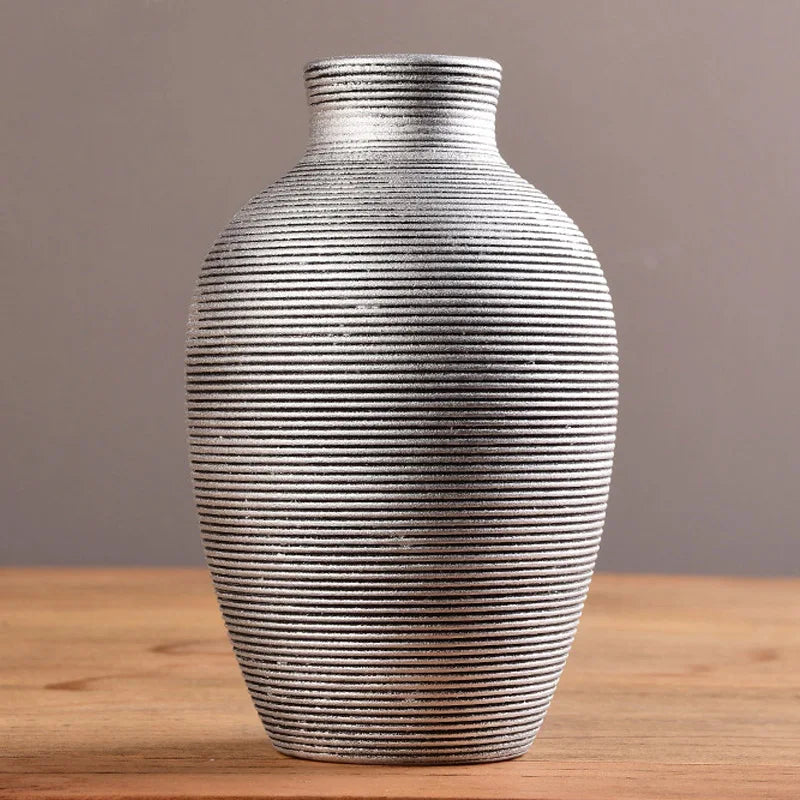 A modern ceramic flower vase with horizontal ridged texture in black and white on a wooden surface.
