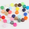 Assorted snap buttons in various colors including green, yellow, purple, pink, and brown for crafting