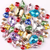 A mix of silver claw setting glass rhinestones in jelly candy AB colors scattered on a white background.