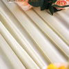 A close-up of peach roses and green leaves arranged on a cream fabric drape.