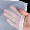 A hand is holding a clear, fine mesh nylon filter bag, demonstrating its texture and use.