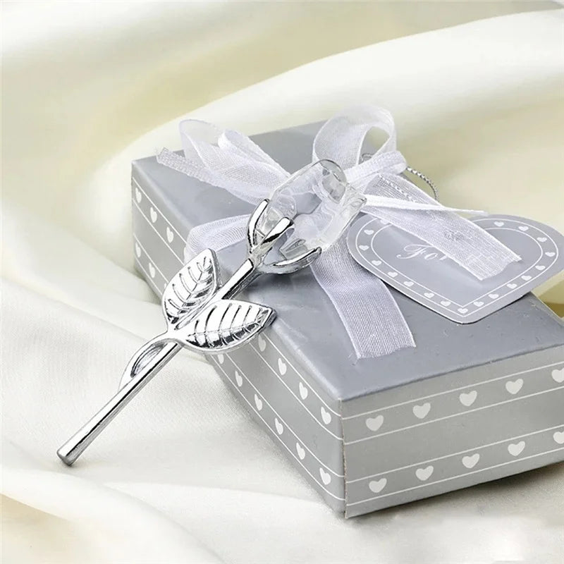 Silver crystal rose artificial flower with a sheer ribbon bow resting on a gray gift box