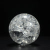 A clear, spherical crystal ball water feature ornament reflecting light against a dark background.