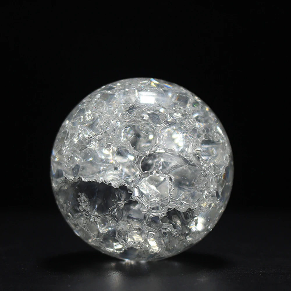 A clear, spherical crystal ball water feature ornament reflecting light against a dark background.