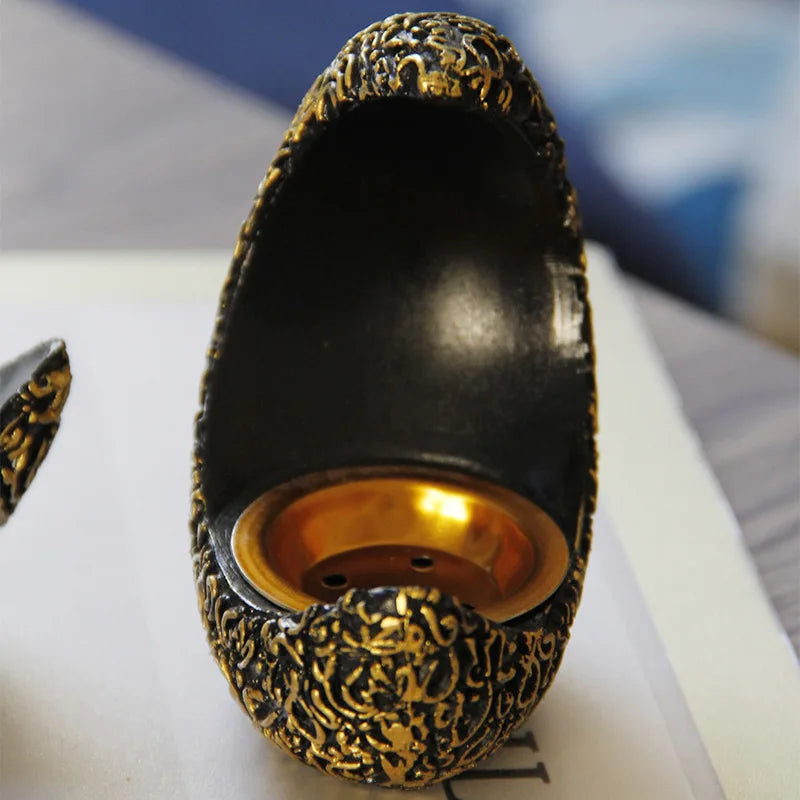 An antique crescent resin incense burner with a dark body and gold-colored decorative finish.