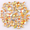 A mix of silver claw setting glass rhinestones in jelly candy AB colors scattered on a white background.