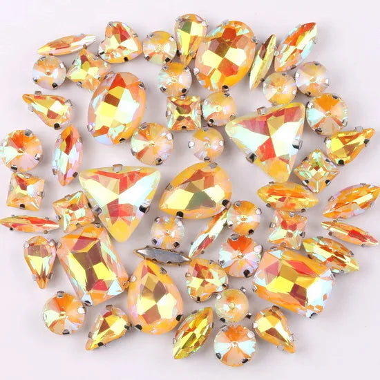 A mix of silver claw setting glass rhinestones in jelly candy AB colors scattered on a white background.