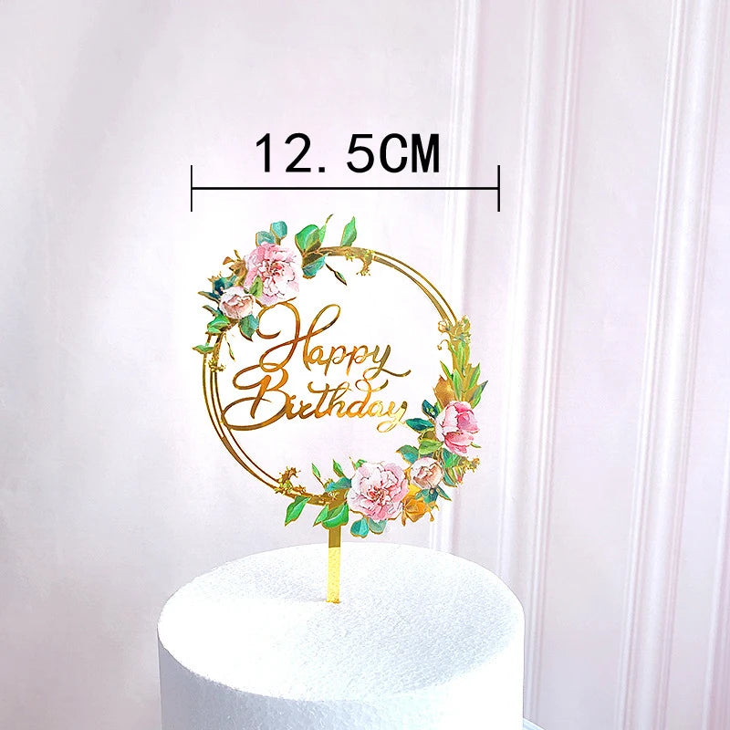 Rose gold acrylic happy birthday cake topper featuring floral accents on a white cake.