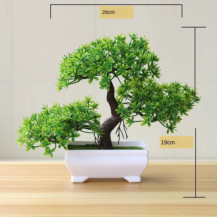Artificial bonsai tree in a white rectangular pot with green foliage, displayed on a wooden surface.