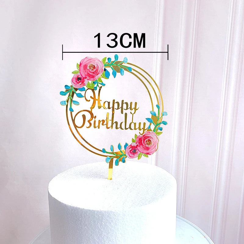 Rose gold acrylic happy birthday cake topper featuring pink roses and green foliage on a white cake.