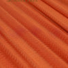 Close-up of orange chiffon fabric draped in soft folds for wedding arch decoration.
