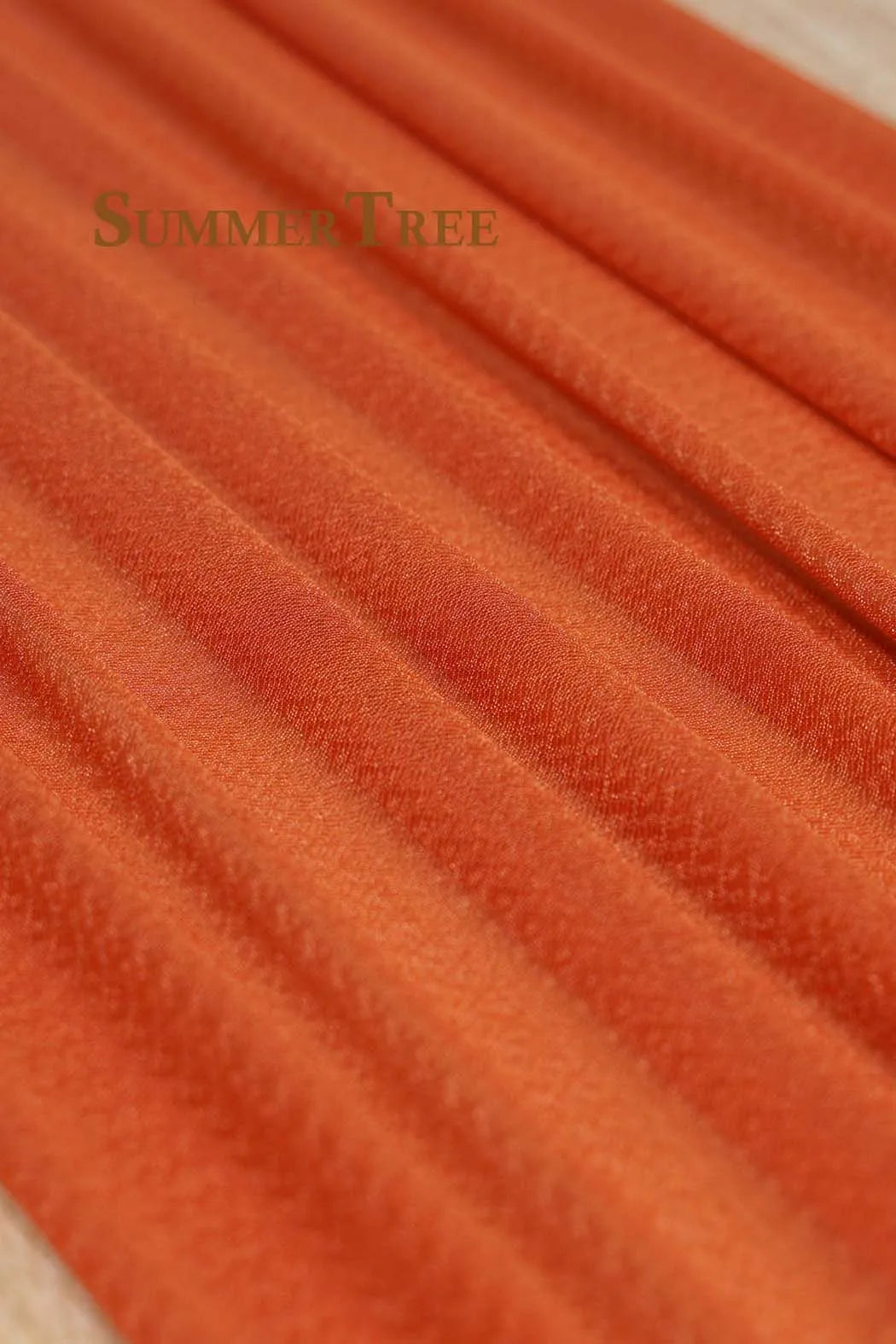 Close-up of orange chiffon fabric draped in soft folds for wedding arch decoration.