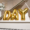 Gold foil letter balloons spelling out DAY displayed on a white ledge.