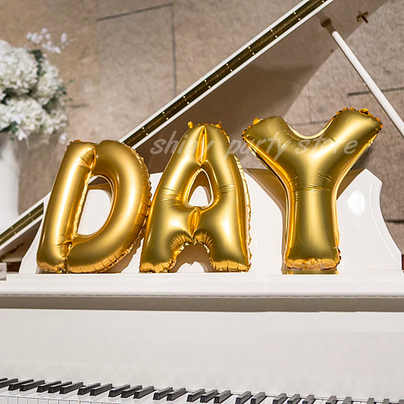 Gold foil letter balloons spelling out DAY displayed on a white ledge.