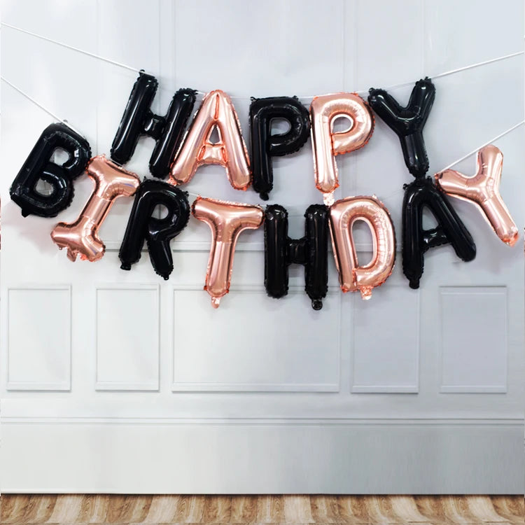 A string of thirteen foil letter balloons spelling out HAPPY BIRTHDAY in rose gold and black colors.