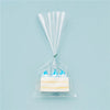 A clear cellophane gift bag with a gold twist tie holds a rectangular white candle.