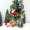 Hand-painted wooden deer Christmas ornaments hanging on a green fir tree.