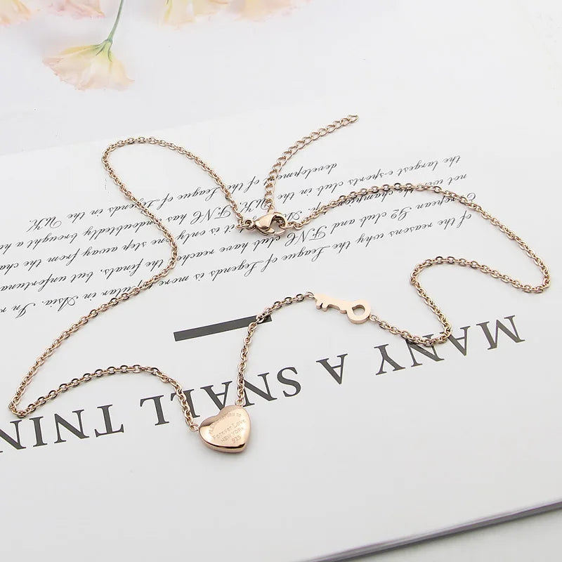 A delicate gold-toned necklace featuring a heart lock key pendant on a thin chain, displayed on a white background.