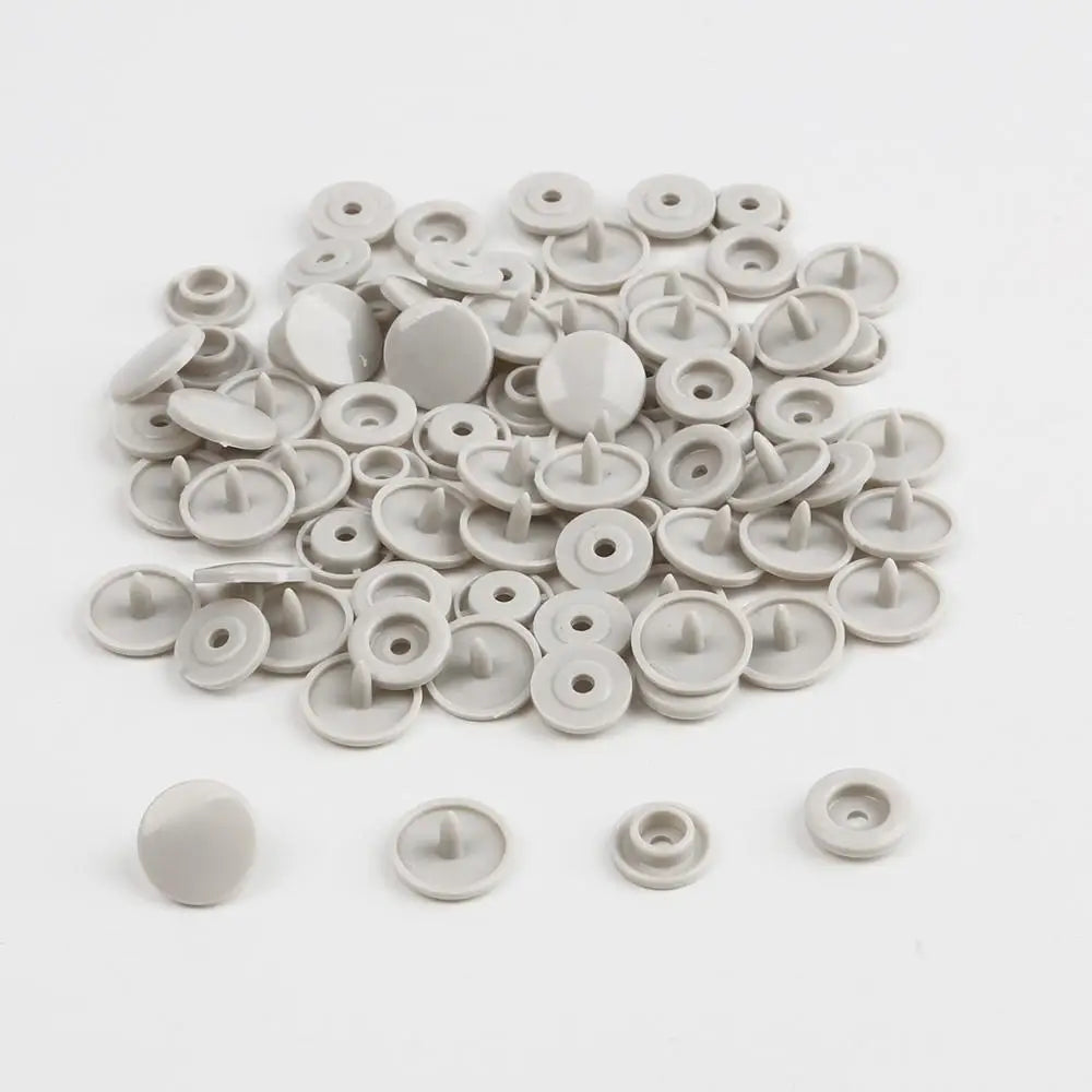 A pile of assorted silver and white snap buttons, measuring 12mm and 10.5mm, for crafting.