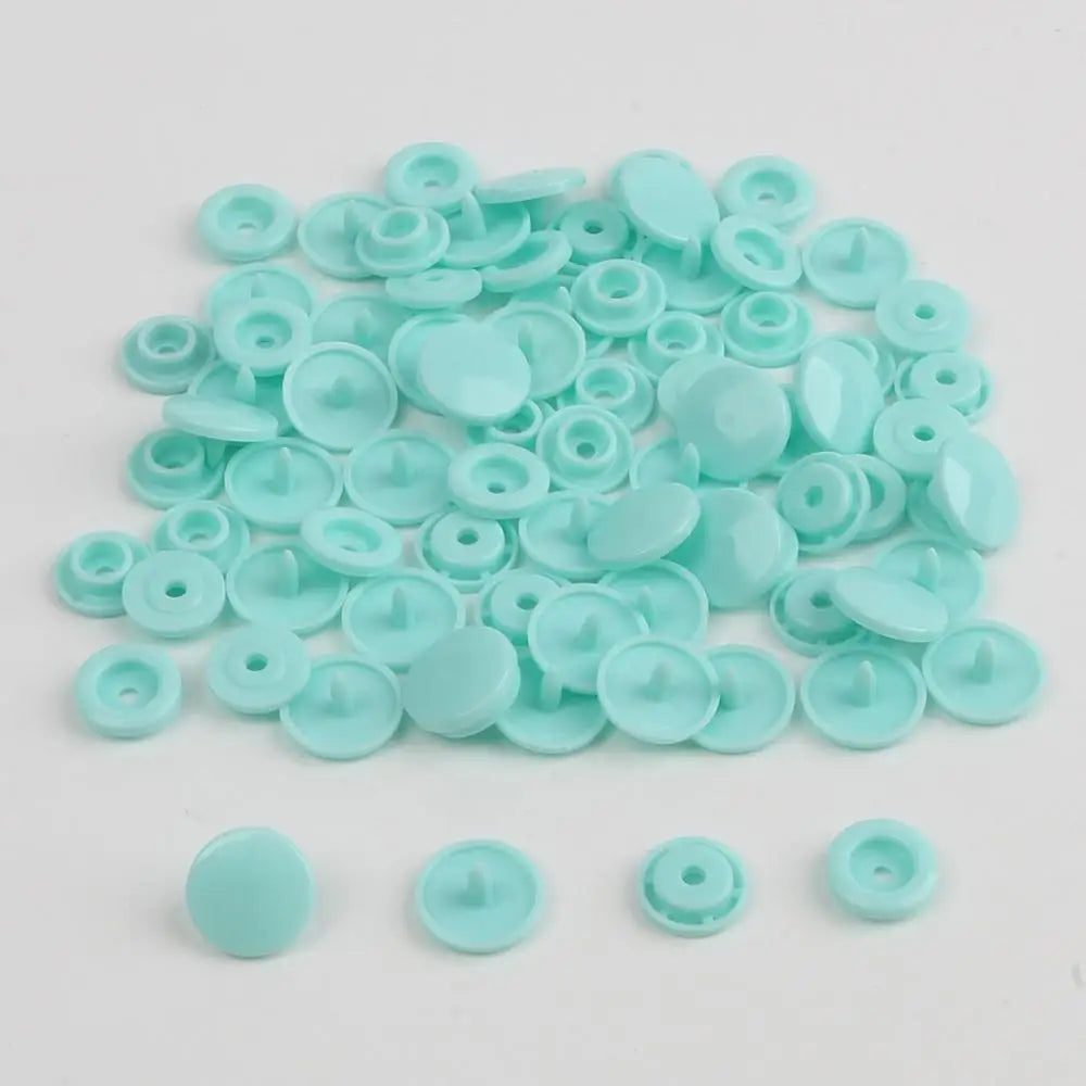 A pile of assorted light blue snap buttons, measuring 12mm and 10.5mm, for crafting.