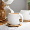 White ceramic coffee mugs displayed on natural bamboo wood stands.
