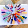 A collection of colorful natural crystal point prisms arranged on a white surface.
