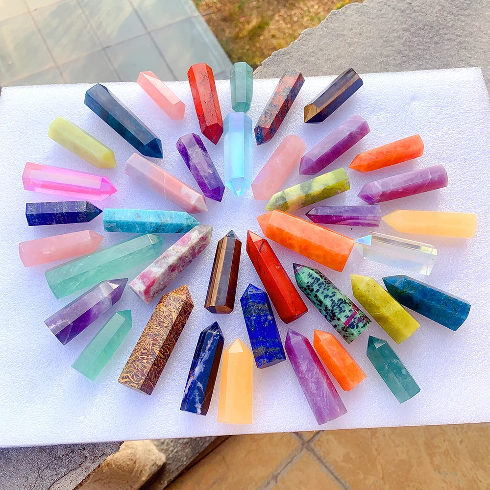 A collection of colorful natural crystal point prisms arranged on a white surface.