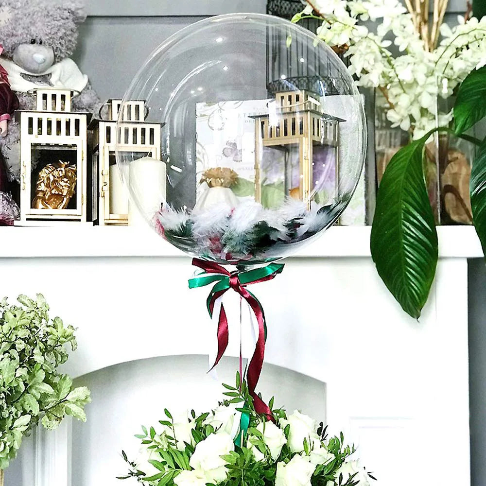 Clear balloons filled with greenery and flowers displayed on a white mantelpiece.
