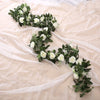 A green and white silk rose hanging vine garland draped on sheer fabric.