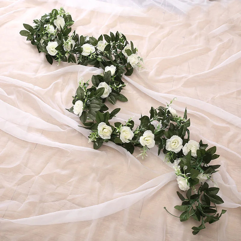A green and white silk rose hanging vine garland draped on sheer fabric.