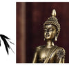 A close-up of a golden Buddha statue with intricate details, set against a dark wooden background.