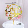 Rose gold acrylic happy birthday wreath with pink and purple flowers on a white cake stand