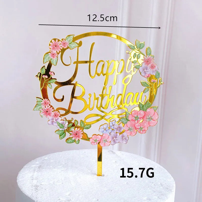 Rose gold acrylic happy birthday wreath with pink and purple flowers on a white cake stand