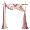 A sheer chiffon fabric drape in shades of pink and ivory is displayed hanging from a wooden cross structure.