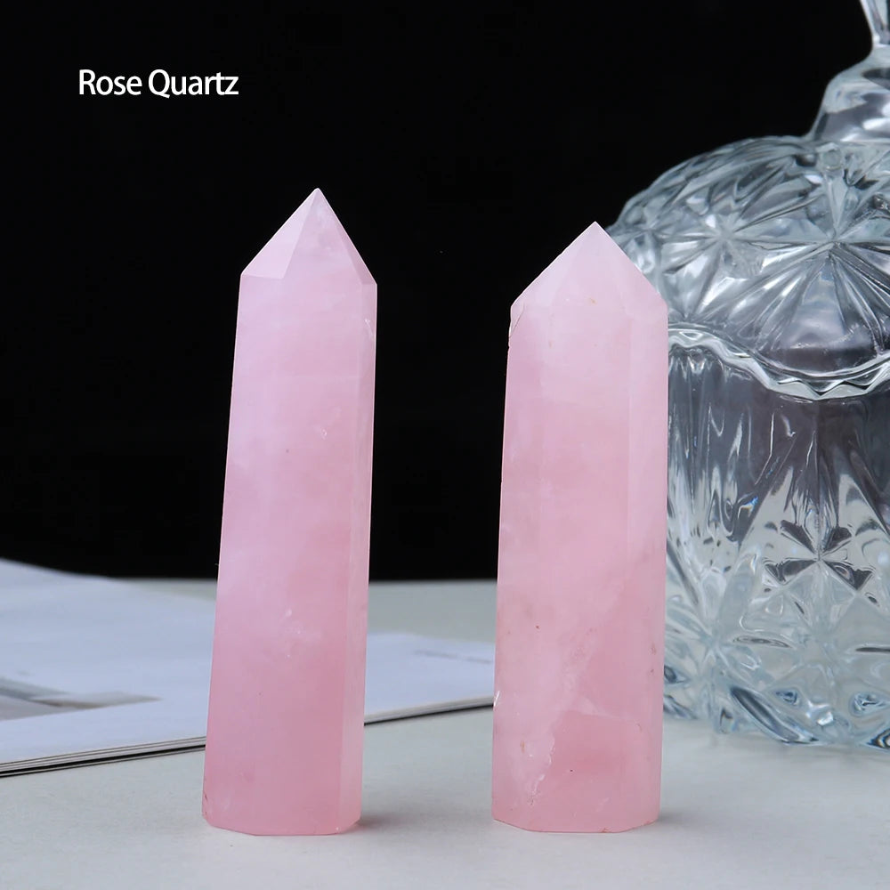 A pink Rose Quartz crystal point prism tower next to a clear glass vessel.