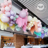 A ceiling display of pastel candy balloons in pink, purple, and green for party decorations.