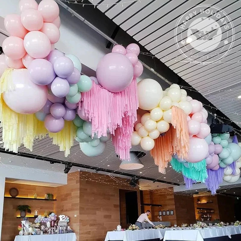 A ceiling display of pastel candy balloons in pink, purple, and green for party decorations.