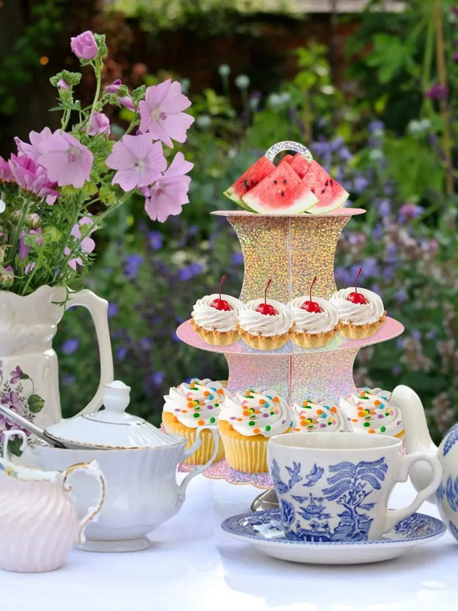 A 3-tier cardboard cupcake stand decorated with watermelon slices and cupcakes set on a white table.