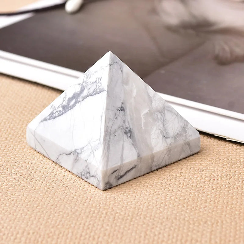 Cristal piramidal de mármol blanco sobre una superficie beige junto a una foto.