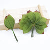 A set of twelve silk leaf artificial plant stems with vases displayed on a wooden board.