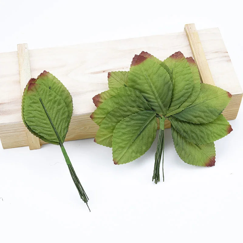 A set of twelve silk leaf artificial plant stems with vases displayed on a wooden board.