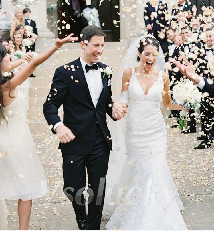 A bride and groom are walking through guests who are showering them with silk rose petals during their wedding exit.