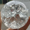 A clear crystal ball water feature ornament is held in a hand, showing its faceted surface.