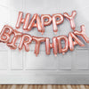 A pink rose gold foil letter balloon banner spelling out Happy Birthday decoration.