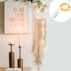 Boho macrame dream catcher wall decor featuring a white circular design with hanging fringe and a glowing light.