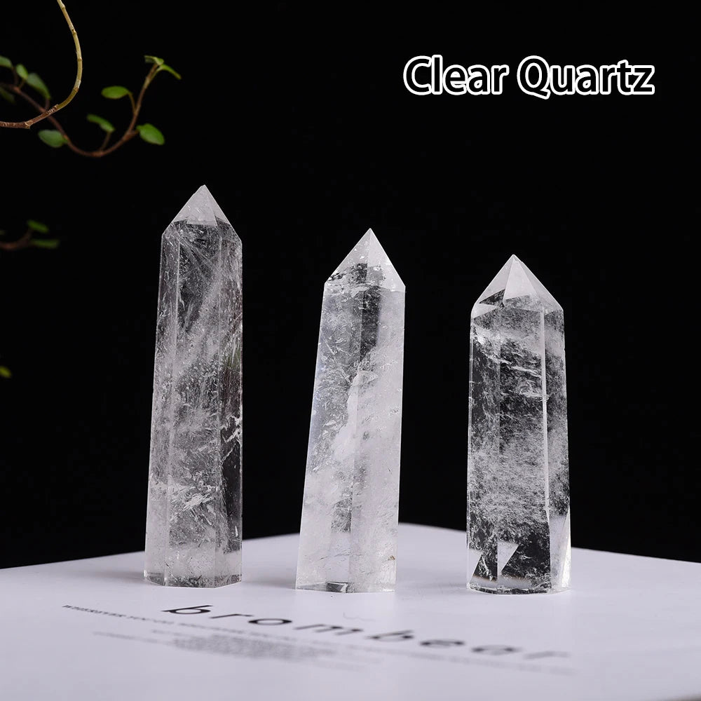 Three clear quartz crystal points of varying sizes displayed on a white surface against a black background.