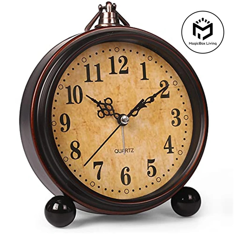 A vintage metal battery alarm clock with a round face and Roman numerals, sitting on a surface.