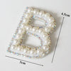 White pearl alphabet letter patch with iridescent rhinestones on a white background